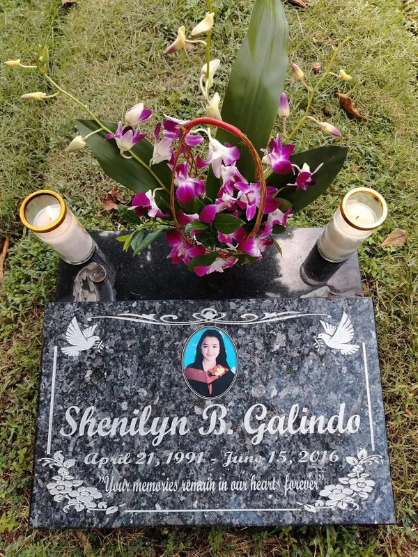 Blue pearl granite lapida installed at a gravesite, with candles and orchids placed beside it